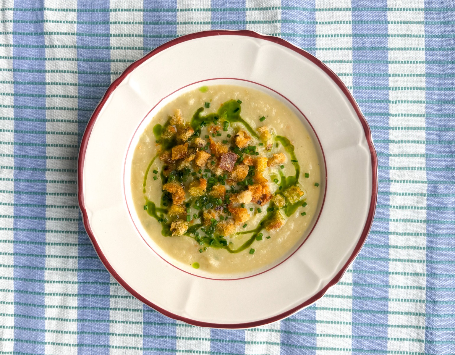 Knolselderij soep met gekarameliseerde uien, parmezaan croutons en bieslookolie