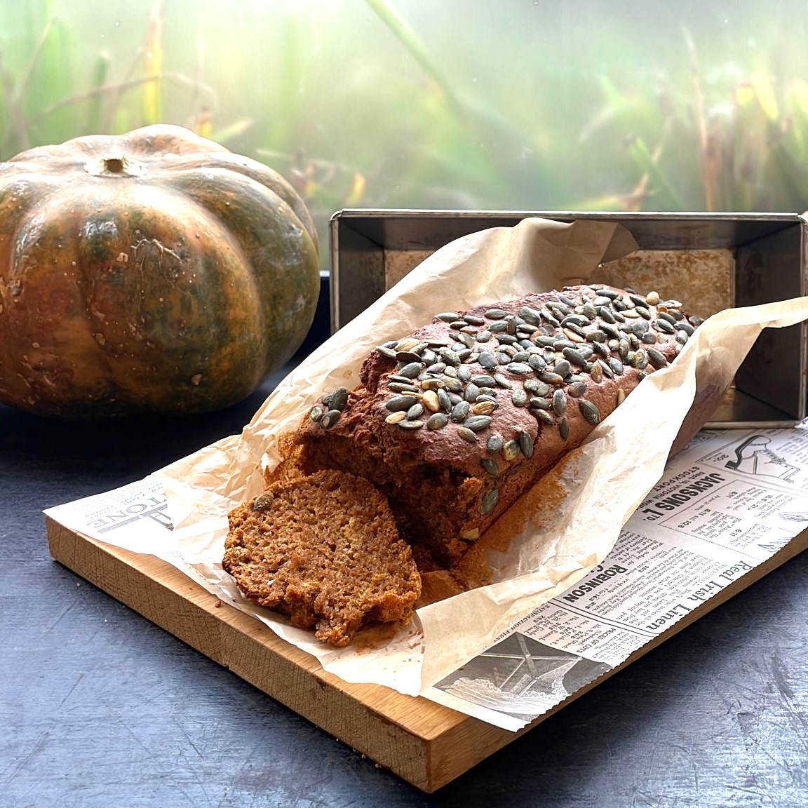 Het eindresultaat: de pompoencake. Gepresenteerd op een houten plak met op de achtergrond pompoenen